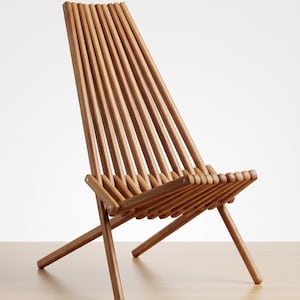 May include: A folding chair constructed from multiple parallel light brown wooden slats. The chair features a tall, angled backrest and a low seat, both formed by the continuous arrangement of these rounded wooden rods connected by metal hardware.