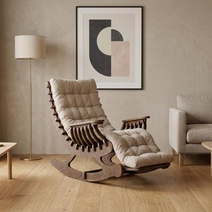 May include: A dark wood rocking chair featuring a curved frame with a slatted back design and a thick, tufted beige cushion that covers the seat and backrest. The chair has integrated armrests and a curved base for a smooth rocking motion.