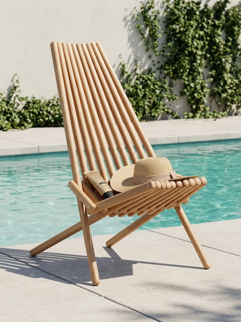 May include: A light-colored wooden lounge chair with a slatted back and seat design. A beige straw hat with a brown ribbon and a small tan tube of sunscreen are resting on the seat of the chair, which features a folding frame construction.