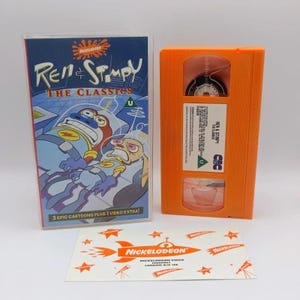May include: A Ren & Stimpy The Classics VHS tape in an orange plastic shell, its clear plastic case with blue cover art featuring the characters in space suits, and a rectangular white paper insert with orange Nickelodeon rocket graphics.