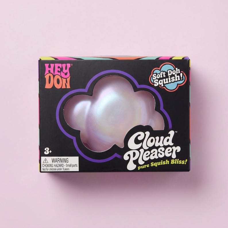 May include: A black rectangular box containing a pearlescent, cloud-shaped squishy toy. The packaging features the text HEY DON, Soft Doh Squish!, Cloud Pleaser, and pure Squish Bliss!, along with a warning label for small parts and a 3+ age rating.