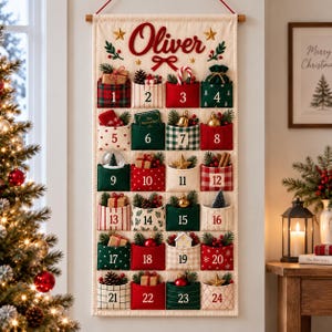 Könnte beinhalten: Ein cremefarbener Wand-Adventskalender aus Stoff mit dem Namen Oliver in roter Schrift oben. Er verfügt über vierundzwanzig nummerierte Taschen in roten, grünen und weißen Mustern, die jeweils mit weihnachtlichen Dekorationen gefüllt sind.