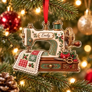 May include: A flat, acrylic Christmas tree ornament shaped like a vintage sewing machine in cream and green with gold accents. It features the name Emily, a red pincushion, scissors, and a quilt with red and green squares hanging from the needle.