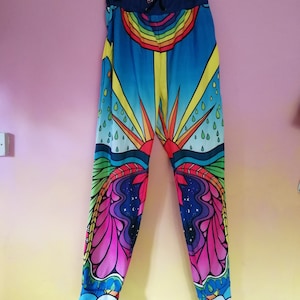 May include: Colorful sweatpants with a rainbow, sun, and raindrops design. The pants are blue, yellow, pink, green, and orange.