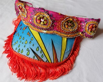 Blue and yellow visor with pink trim and orange tassels. Festival, rave