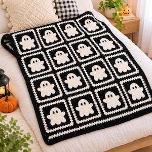 May include: A rectangular crochet blanket featuring a repeating pattern of white ghost motifs centred within individual black square blocks. The blanket is constructed from multiple joined squares, each displaying a small, friendly ghost figure.