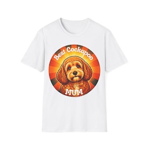Könnte beinhalten: Ein weißes kurzärmeliges T-Shirt mit einer kreisförmigen Grafik auf der Brust. Die Grafik zeigt einen braunen Cockapoo-Hund vor einem rot-orangen Strahlenhintergrund, mit dem weißen Text Best Cockapoo MUM in einem Bogen darüber.