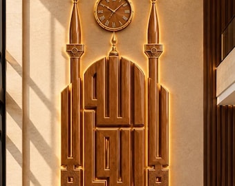 May include: A wall-mounted wooden decorative piece featuring the Arabic calligraphy for Allah, flanked by two tall minaret-style towers. Above the central structure sits a round analog clock with Roman numerals and gold-toned hands.