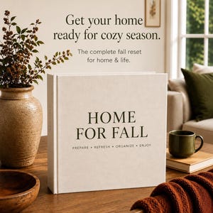 Könnte beinhalten: Ein weißes Hardcover-Buch mit dem Titel HOME FOR FALL und dem Untertitel PREPARE • REFRESH • ORGANIZE • ENJOY. Darüber steht der Text: Get your home ready for cozy season. The complete fall reset for home & life. Das Buch liegt auf einem Holztisch.