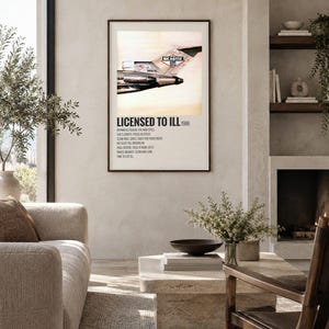May include: A framed wall art print featuring the Beastie Boys Licensed to Ill 1986 album cover. The artwork displays the tail section of a Boeing 727 airplane with the band logo, followed by a tracklist printed in black text on a white background.
