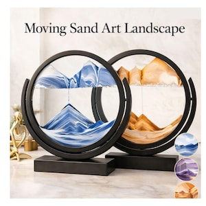 Peut inclure: Deux cadres circulaires Moving Sand Art Landscape avec des bases rectangulaires noires. L'un contient du sable bleu et blanc formant des montagnes, l'autre du sable doré et blanc. Des encarts circulaires montrent des variantes de sable bleu, violet et doré.