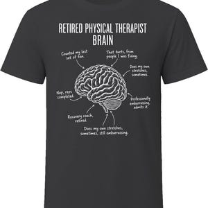 May include: A dark gray short-sleeve t-shirt featuring a white graphic of a human brain. The text reads: RETIRED PHYSICAL THERAPIST BRAIN, with arrows pointing to various labels including Counted my last set of ten, That hurts, from people I was fixing, Does my own stretches, sometimes, Nap, reps completed, Professionally embarrassing, admits it, Recovery coach, retired, and Does my own stretches, sometimes, still embarrassing.