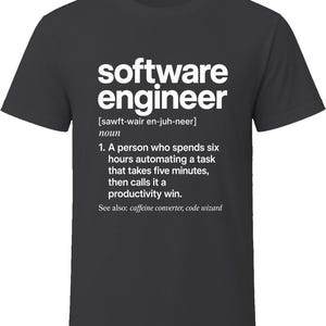 May include: A charcoal grey t-shirt featuring white text that defines a software engineer as a person who spends six hours automating a task that takes five minutes, then calls it a productivity win, with the phrase see also: caffeine converter, code wizard.