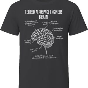 May include: A charcoal gray t-shirt featuring a white graphic of a human brain with labels pointing to different sections. The text reads: RETIRED AEROSPACE ENGINEER BRAIN, along with phrases like Model rockets with grandkids, to absurd tolerances.