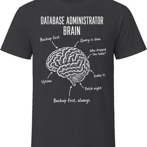 May include: A charcoal gray t-shirt featuring a white graphic of a human brain. The text reads: DATABASE ADMINISTRATOR BRAIN, with arrows pointing to labels: Backup first., Query is slow., Who dropped the table?, Index it., Patch night., Backup first, always.