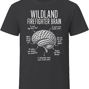 May include: A charcoal gray t-shirt featuring a white graphic of a human brain with labels pointing to different sections. The text reads: WILDLAND FIREFIGHTER BRAIN, I can dig that line, I need more fresh socks, Where did my pulaski go, Why did the wind shift NOW, 14 days, one shower, no complaints, Anchor and flank. Always, and I definitely need more fresh socks.