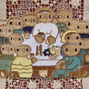 May include: A ceramic plaque depicting a gathering of stylized figures around a table. The figures are in various colors, including green, yellow, and blue. The table is set with utensils and a floral arrangement. The plaque has a rustic, handmade appearance.