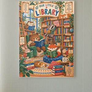 May include: A colourful wall art print titled Our Little Library featuring an illustration of an owl, raccoon, bear, fox, rabbit, and hedgehog reading books in a cosy room filled with wooden bookshelves, plants, and stacks of books with text.