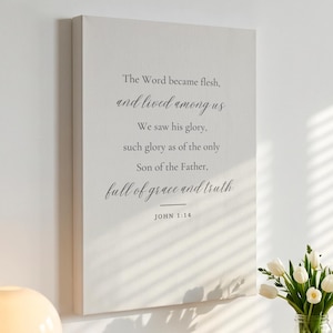 May include: A rectangular wall canvas featuring the text: The Word became flesh, and lived among us. We saw his glory, such glory as of the only Son of the Father, full of grace and truth. JOHN 1:14. The text is printed in black on a light gray background.