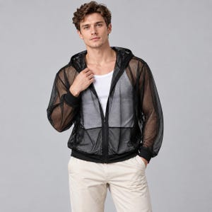 Op de afbeelding: Een zwarte mesh hoodie met ritssluiting, lange mouwen met geribbelde boorden en een capuchon met trekkoord. Het kledingstuk wordt gedragen over een effen wit hemd en een lichte broek, wat de transparante textuur van de stof benadrukt.