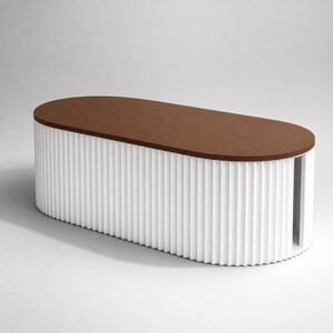 Op de afbeelding: Een ovaalvormige salontafel met een plat, effen bruin bovenoppervlak. De basis van de tafel is geconstrueerd met een wit, verticaal gegroefd exterieurontwerp dat de gehele omtrek omsluit, waardoor een consistente geribbelde textuur ontstaat.