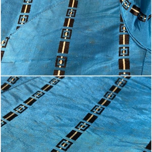 May include: Close-up of a blue fabric with black and white geometric patterns. The fabric has a subtle sheen and a slightly textured surface.