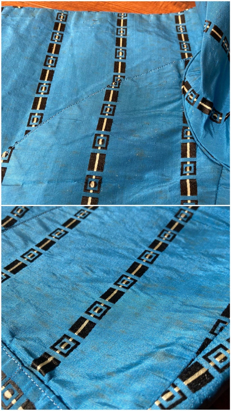 May include: Close-up of a blue fabric with black and white geometric patterns. The fabric has a subtle sheen and a slightly textured surface.