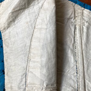 May include: Close-up of the inside of a garment, showing the white cotton lining and the blue and white patterned fabric of the outer layer. The seams are visible, and the fabric is slightly wrinkled.
