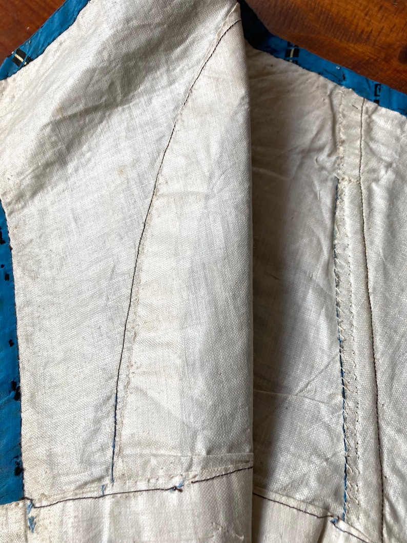 May include: Close-up of the inside of a garment, showing the white cotton lining and the blue and white patterned fabric of the outer layer. The seams are visible, and the fabric is slightly wrinkled.