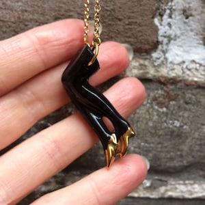 Handgemaakte porseleinen halve poppenpoten aan een lange jasseronketting in zwart en goud