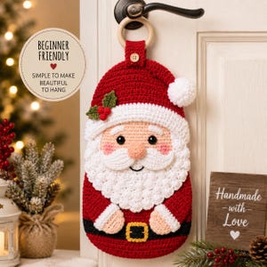 May include: A crochet Santa Claus wall hanging featuring a red hat with a white pom-pom, a white beard, a black belt with a yellow buckle, and a small wooden ring at the top for hanging. The design includes green holly leaves and red berries.