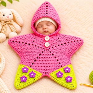 May include: A star-shaped crochet baby bunting in bright pink and lime green. The pink section features a hood and two white buttons, while the lime green bottom points are decorated with small purple and white crochet flowers.