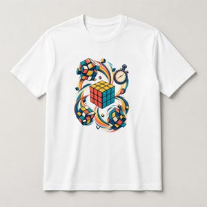 May include: A white short-sleeve t-shirt featuring a central graphic of a multi-colored puzzle cube surrounded by smaller floating cubes and a stopwatch, all accented by swirling colorful lines in shades of blue, orange, and yellow.