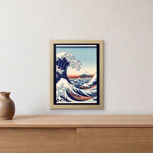 May include: A framed print of a Japanese woodblock style artwork featuring a large, cresting blue wave with white foam, several boats navigating the turbulent water, and a distant snow-capped mountain against a pale sky in a gold frame.