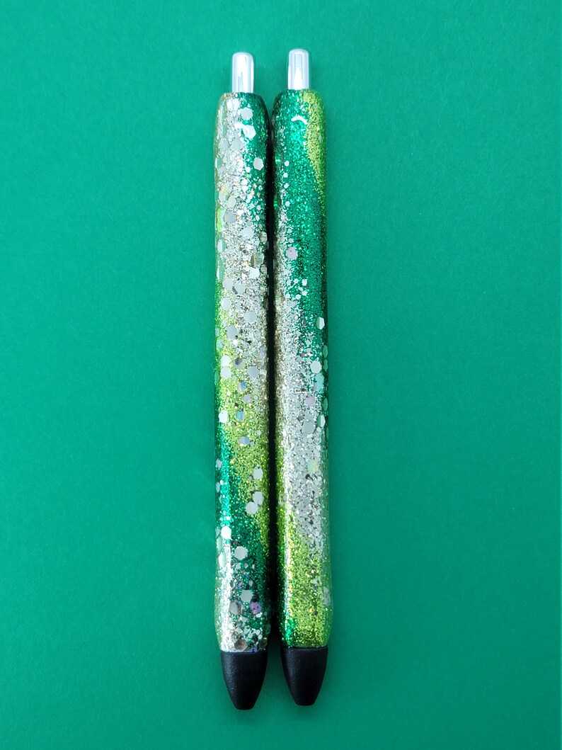 May include: Two green and silver glitter pens with black caps.
