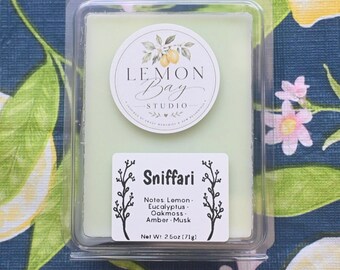 Könnte beinhalten: Ein hellgrünes Duftwachs in einer durchsichtigen Kunststoffverpackung. Das obere Etikett zeigt das Logo von Lemon Bay Studio. Das untere Etikett trägt die Aufschrift Sniffari, listet Zitrone, Eukalyptus, Eichenmoos, Amber, Moschus und 71g auf.