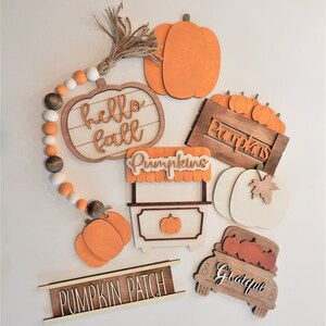 May include: A set of wooden autumn decorations featuring pumpkins, a truck, and signs that say "hello fall", "pumpkins", "pumpkin patch", and "grateful".