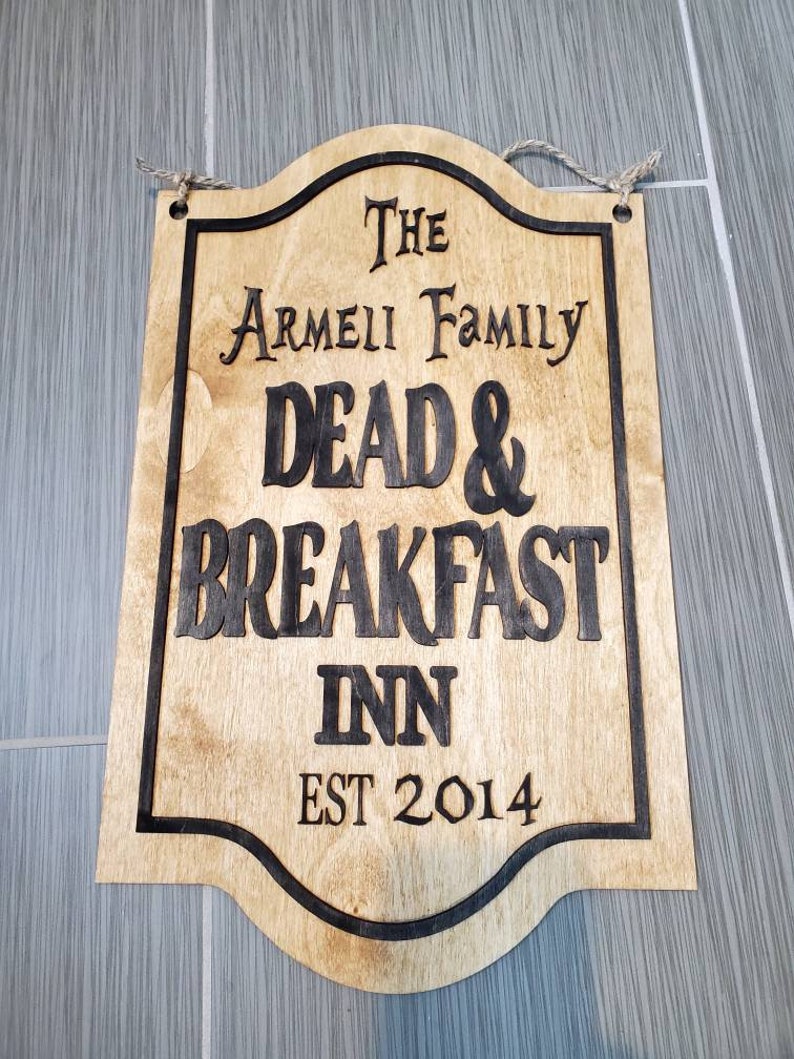 May include: A wooden sign with black lettering that reads "The Armeii Family Dead & Breakfast Inn Est 2014".