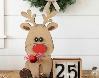 May include: Wooden reindeer Christmas decoration with a red nose, a red and white checkered bow, and a small bell. The decoration includes a block calendar displaying the number 25. The item measures 6x7 inches.