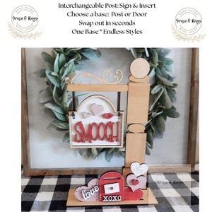 May include: Wooden interchangeable sign with a base and various inserts. The sign features the word "SMOOCH!" and heart and lip accents. Additional inserts include a mailbox with "love" and "XOXO" details.