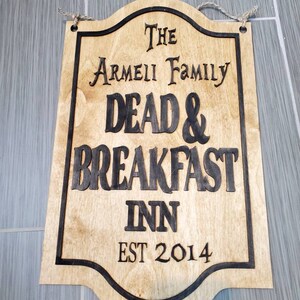 May include: A wooden sign with black lettering that reads "The Armeii Family Dead & Breakfast Inn Est 2014".