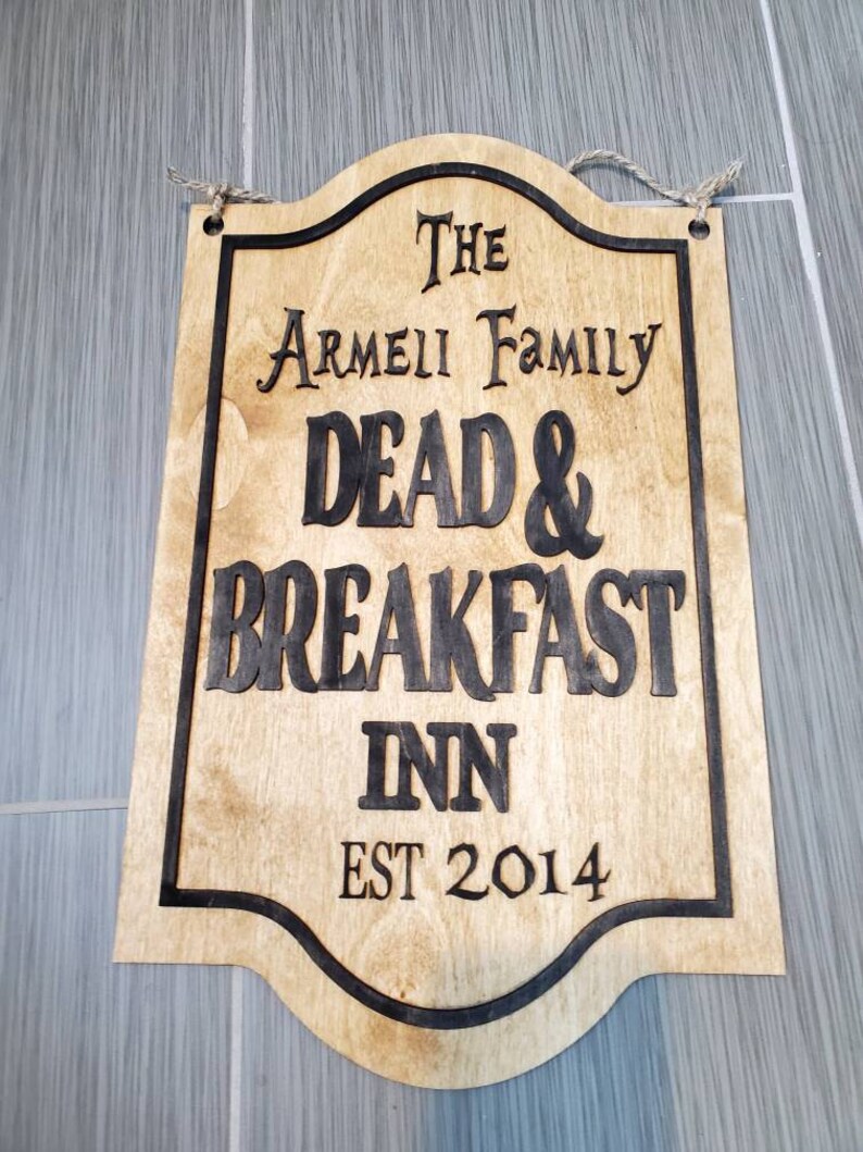 May include: A wooden sign with black lettering that reads "The Armeii Family Dead & Breakfast Inn Est 2014".