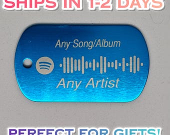 May include: A rectangular blue metal dog tag with rounded corners and a small hole on the left side. The tag features an engraved Spotify logo, a sound wave graphic, and the text Any Song/Album and Any Artist etched into the surface.