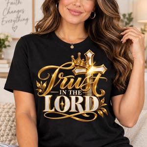 May include: A black short-sleeved t-shirt featuring a graphic design with a gold crown resting on a white cross. The text "Trust IN THE LORD" is printed in a metallic gold and white font, accented with gold leaf flourishes and a bright light effect.