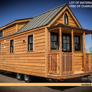 May include: A tiny house on wheels with horizontal wood siding, a dark metal roof, and a front porch with wooden railings. The structure features multiple black-framed windows, a black front door, and a pointed arched window in the gable.