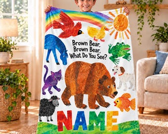 May include: A white fleece blanket featuring the text Brown Bear, Brown Bear, What Do You See? and colourful illustrations of a red bird, yellow duck, blue horse, green frog, purple cat, white dog, orange fish, brown bear, and the word NAME.
