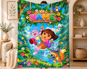 Pode incluir: Uma manta retangular de tecido polar com uma cena vibrante da selva, apresentando a Dora, o macaco Botas e a raposa Raposo. O design inclui uma placa de madeira com o texto NAME, rodeada por flores tropicais, trepadeiras e uma cascata.