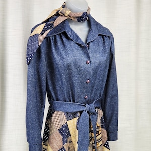 May include: A vintage dress with a denim-style top and a patchwork skirt. The dress has a collared neckline, long sleeves, and a matching belt. The skirt displays a mix of navy, beige, and brown patterns.