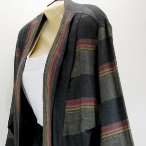 May include: A two-piece outfit featuring a long-sleeved jacket and a skirt. The jacket has a striped pattern in shades of gray, with red and yellow accents. The skirt mirrors the jacket's design.