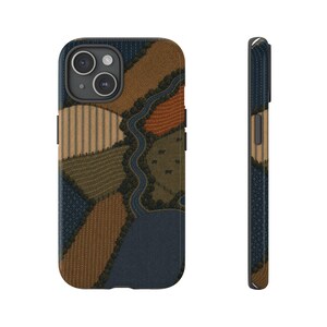 May include: A smartphone case featuring a textured, quilt-like pattern of a rural landscape. The design displays various fields in shades of brown, tan, olive green, and dark blue, separated by a winding dark blue river and small tree lines.